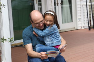 father hugging daughter while they read